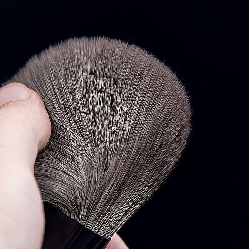 Makeup Brushes Set featuring dense, soft, synthetic grey bristles with a black handle held against a black background.