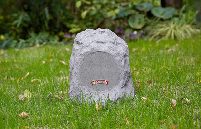 Outdoor Rock Bluetooth speaker in granite grey with textured rock-like design and front metal mesh grill on grass lawn.