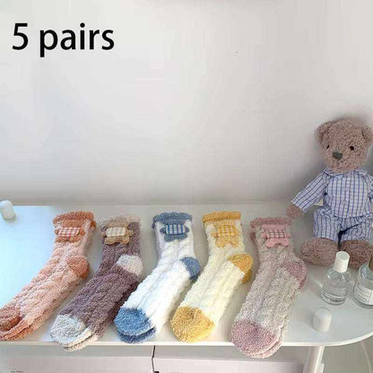 Set of 5 pairs of fuzzy socks in pastel colors including peach, purple, white with blue, white with yellow, and beige with pink accents
